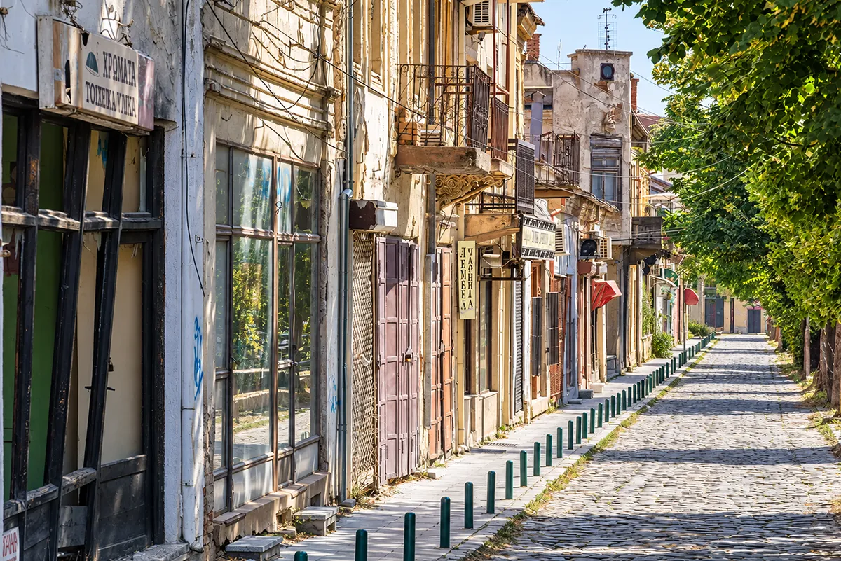 Уличка во Старата чаршија, со дуќани од едната страна и реката Драгор од другата.